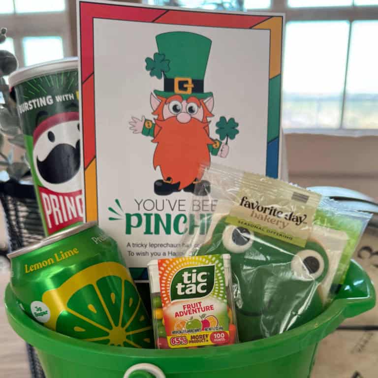 A green bucket full of food items that are green or in green packaging along with some rainbow colored foods with a You've Been Pinched tag tucked inside.