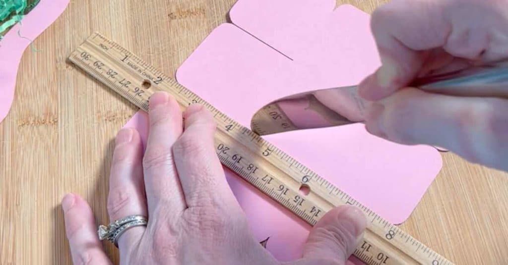 Scoring fold lines for a mini Easter basket using a ruler and the back of a butter knife.
