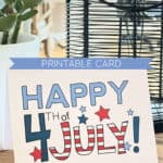 Happy 4th of July Card in red, white, and blue sitting on a table in front of a plant and a vase.
