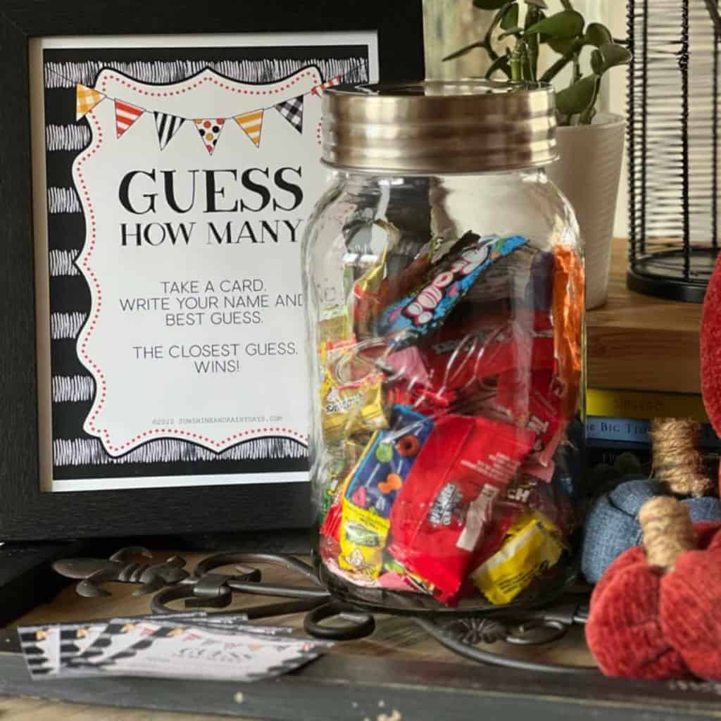 Guess How Many Halloween Game on a table with a sign and jar full of candy.