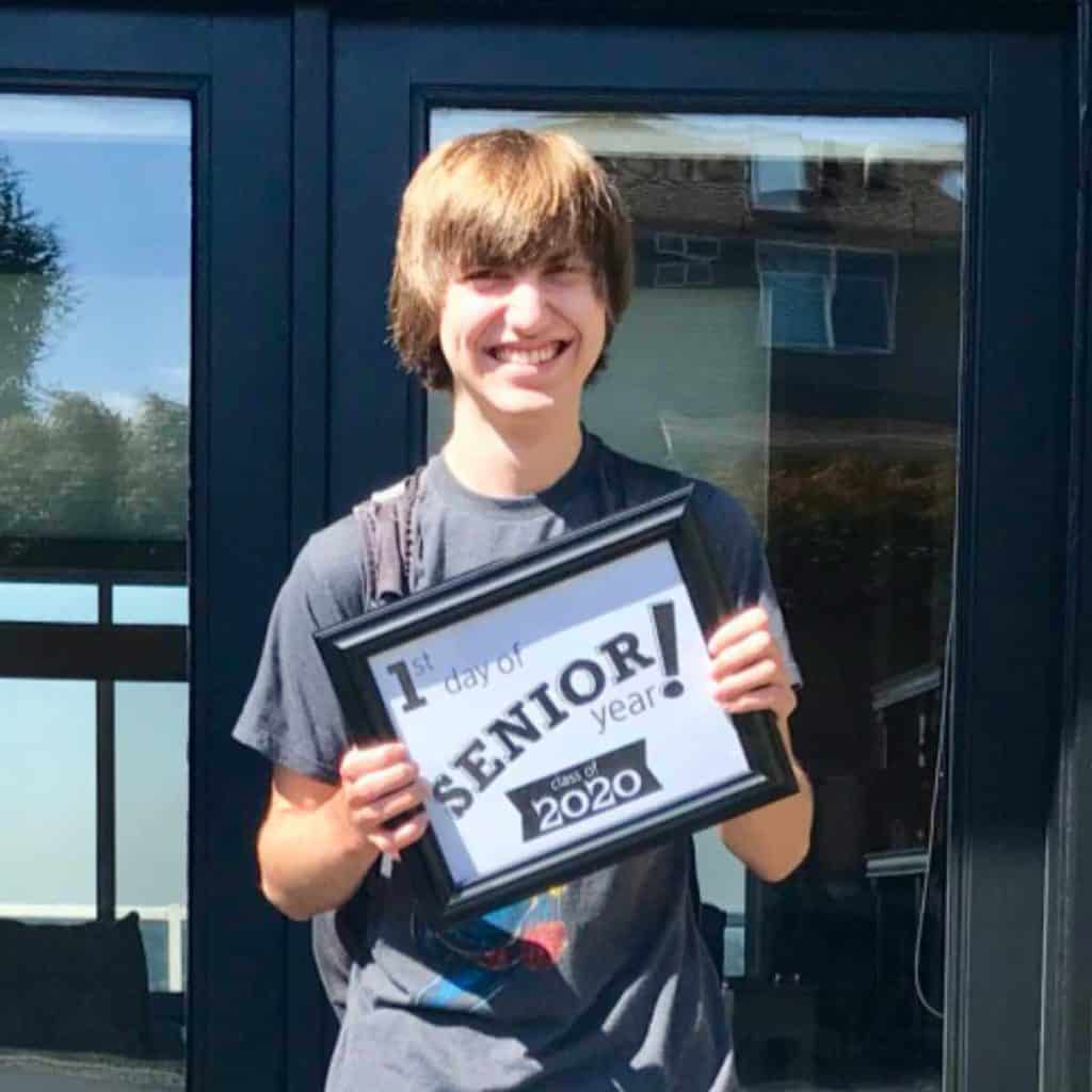 High schooler holding a first day of senior year sign.