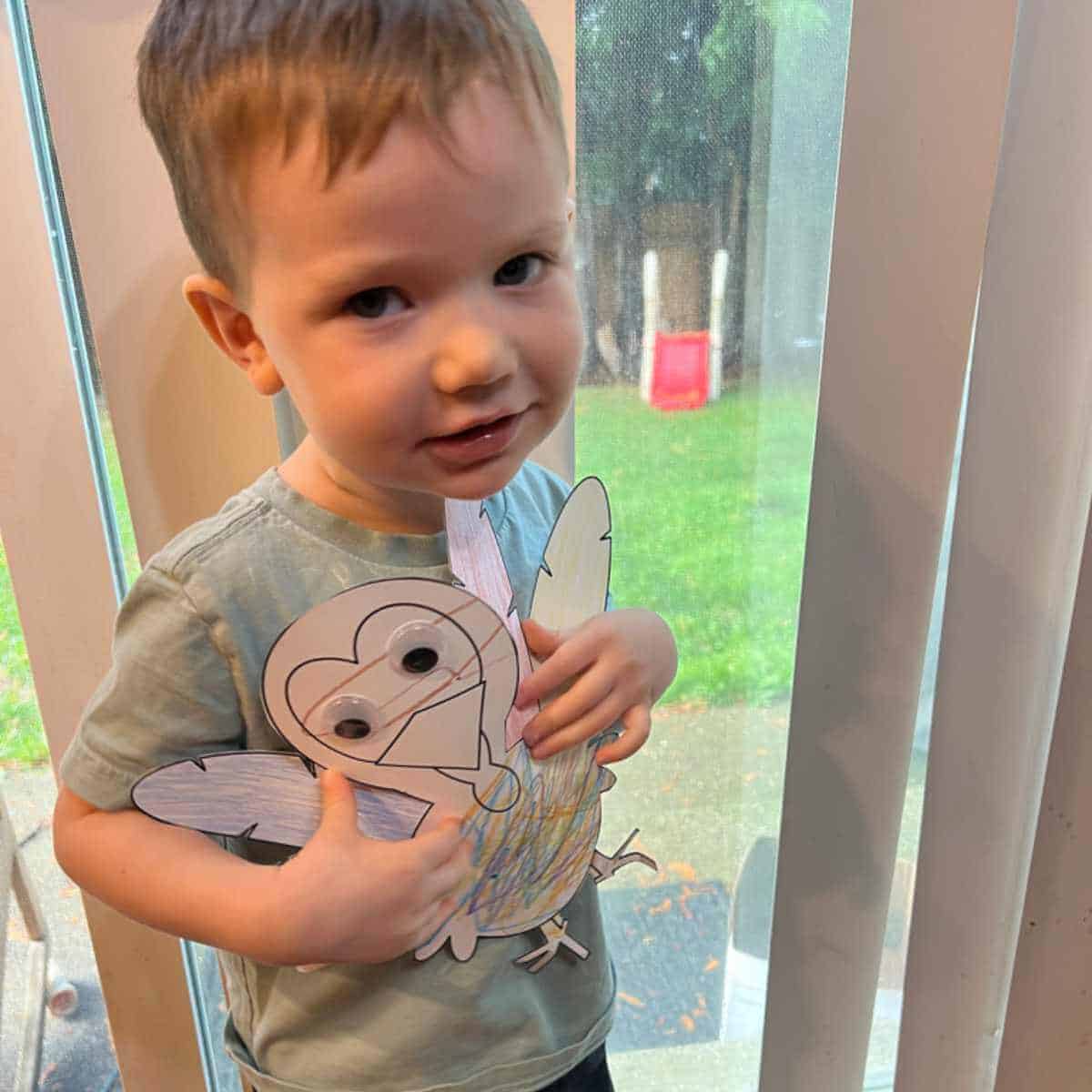 Little boy holding a paper turkey he colored.