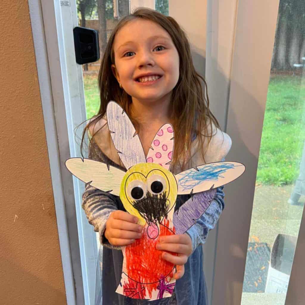 Preschooler holding a paper turkey she colored and cut.