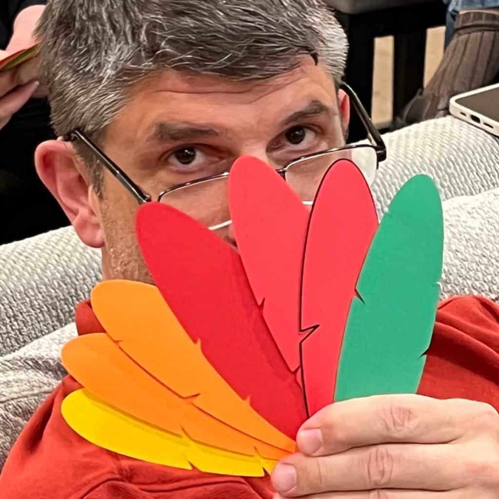 My husband holding up his paper turkey feathers while playing the Who Is Most Like A Turkey game!