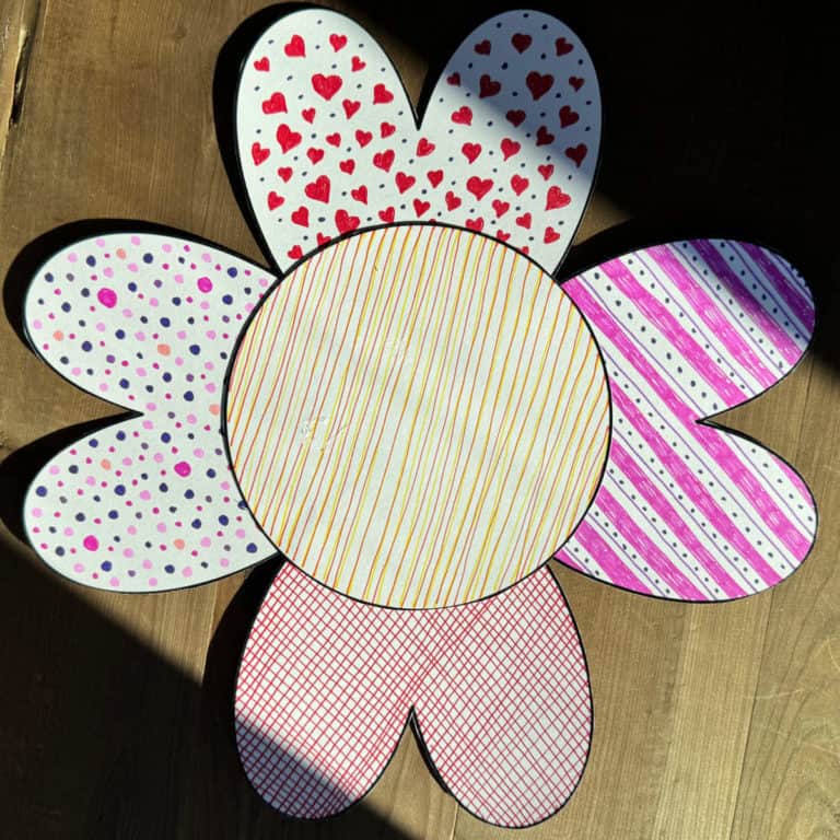 A paper flower made out of the shapes of hearts and a circle, then colored.