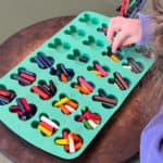 Placing crayons in a bunny silicone mold for melting into a bunny shape.