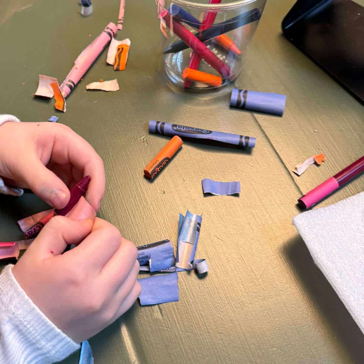 Little girl removing the paper from crayons.