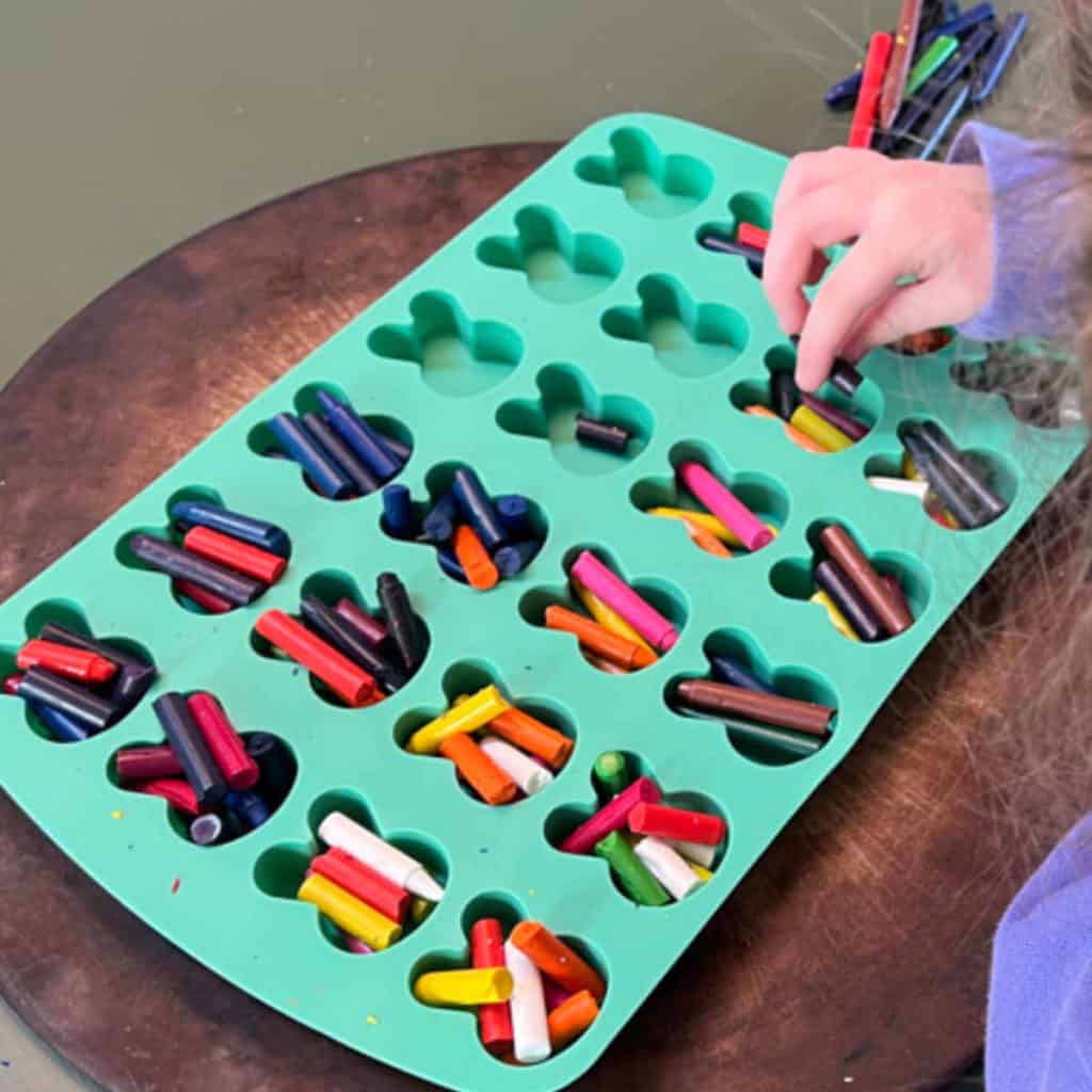 Filling a silicone mold with broken crayons to melt.