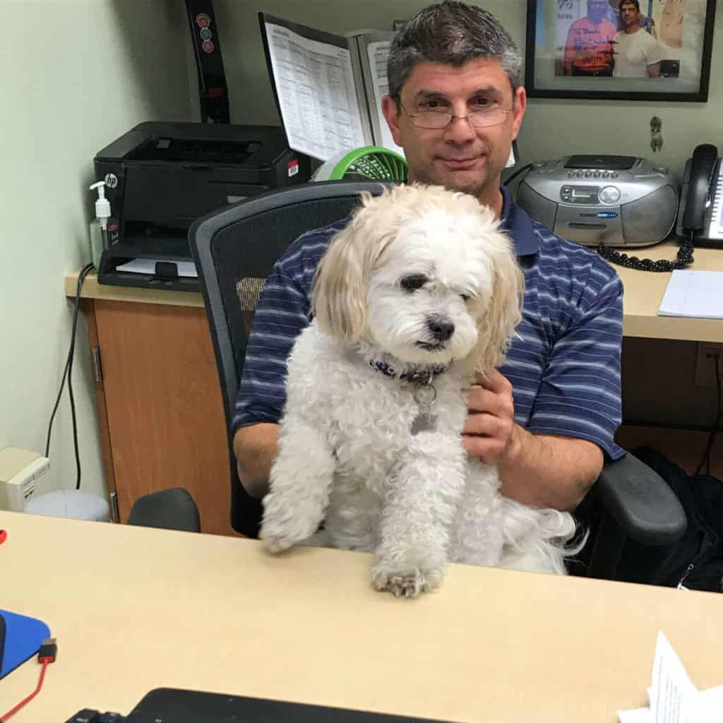 Principal sitting at his desk with his dog.
