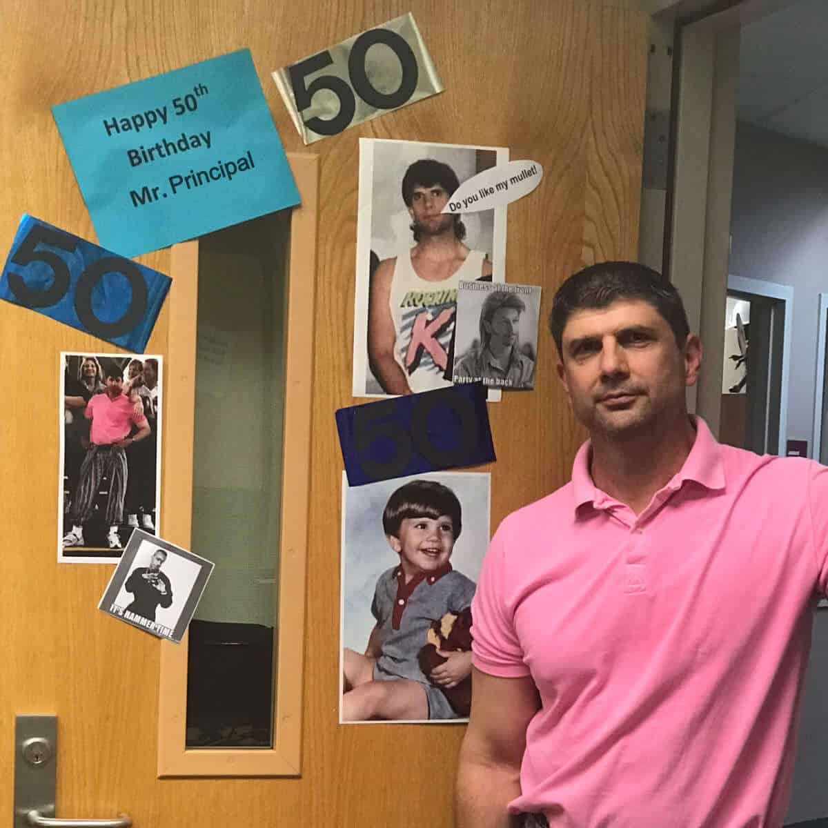 Principal's 50th Birthday. He is standing by his office door that has signs and pictures in celebration of his Birthday.
