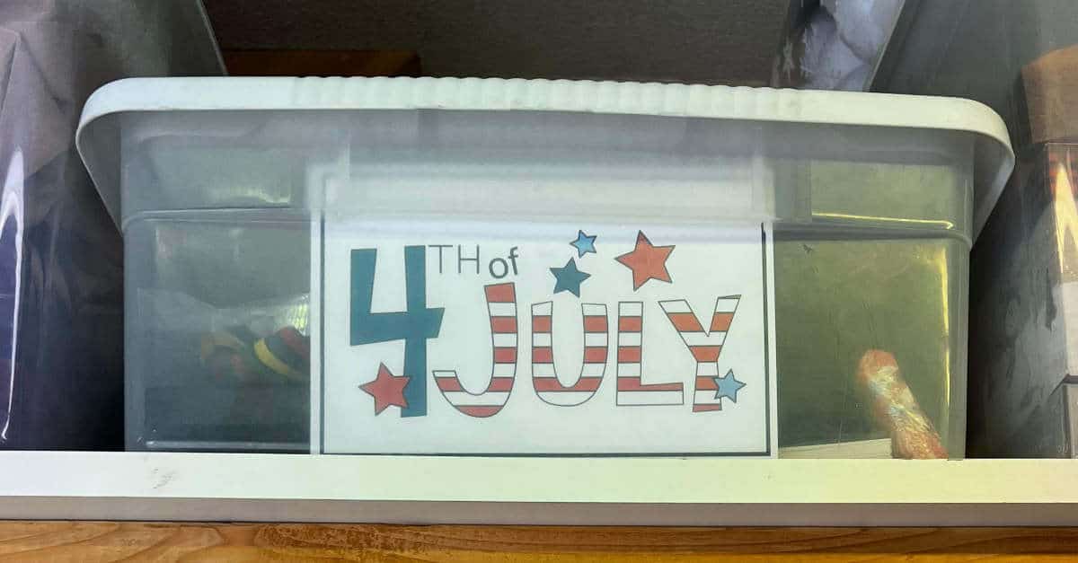 Printable 4th of July storage box label inside the front of a clear plastic storage bin that is sitting on a shelf.