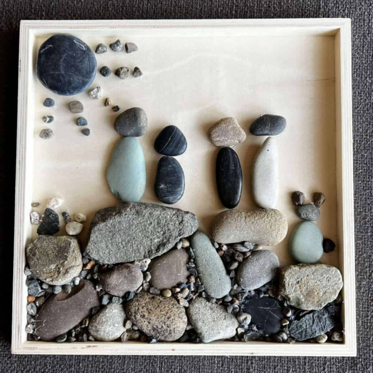 A family portrait made out of rocks and a wood canvas.