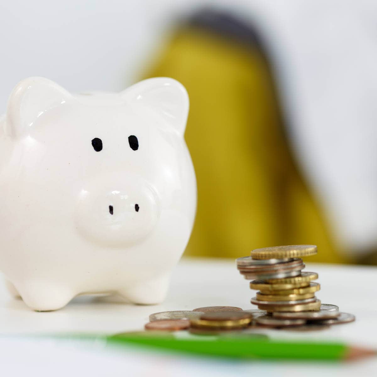 White piggy bank with coins in front of it.