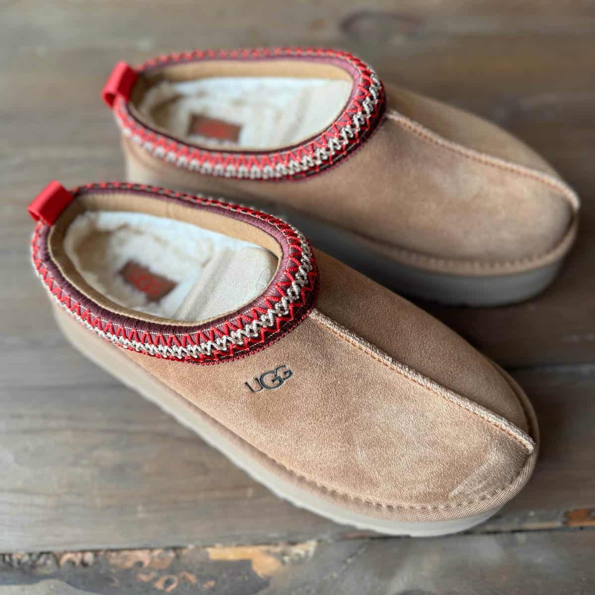 UGG Tazz slippers in the color chestnut, sitting on the floor.