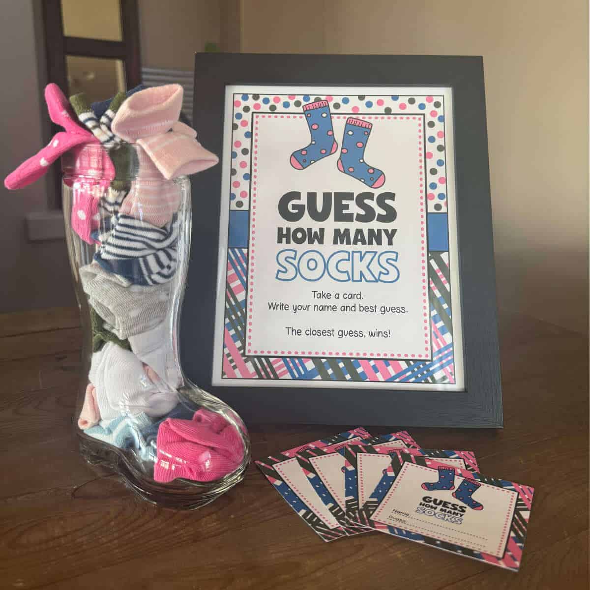 Guess How Many Socks gender reveal party game with sign and a glass boot filled with baby socks.