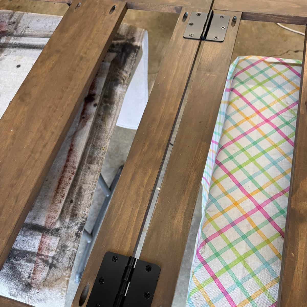 Image of stained wood with two hinges attaching two pieces.