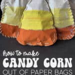 Image of three candy corns made out of paper bags and sitting on a black fireplace hearth.