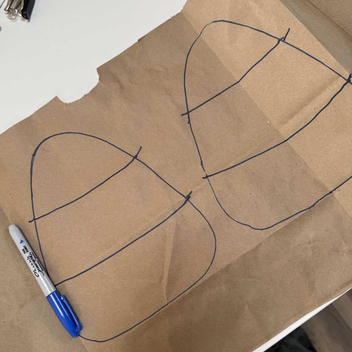 Image of two candy corn shapes and lines drawn onto a brown paper bag with a marker.