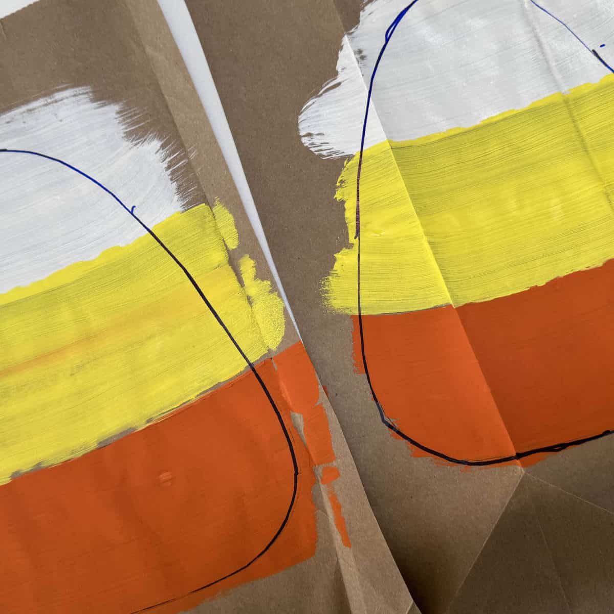 A brown paper bag that has two candy corns painted on it.
