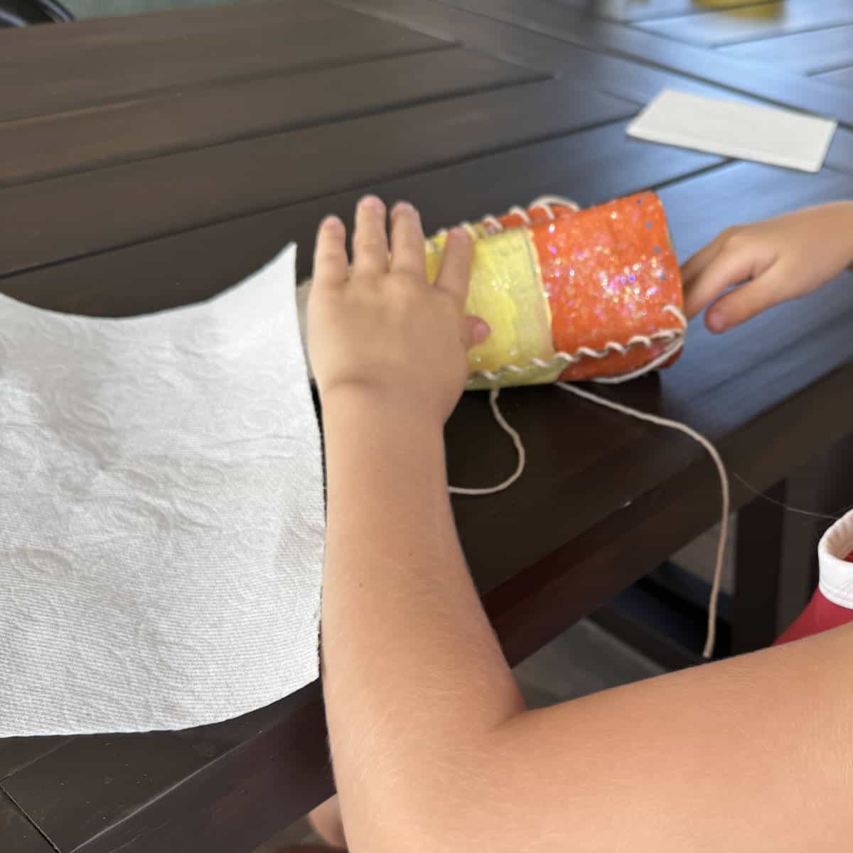 A child stuffing her paper bag candy corn with paper towels to make it fluffy.