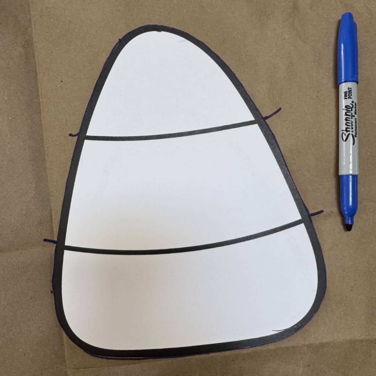 Image of tracing a candy corn template onto a brown paper bag using a blue Sharpie.