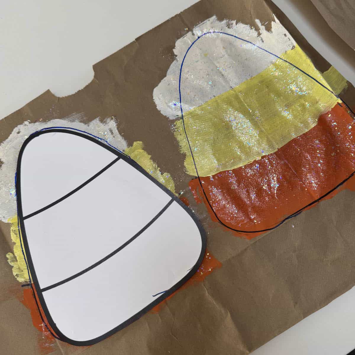 A brown paper bag with candy corn painted on and a candy corn template on top for tracing.