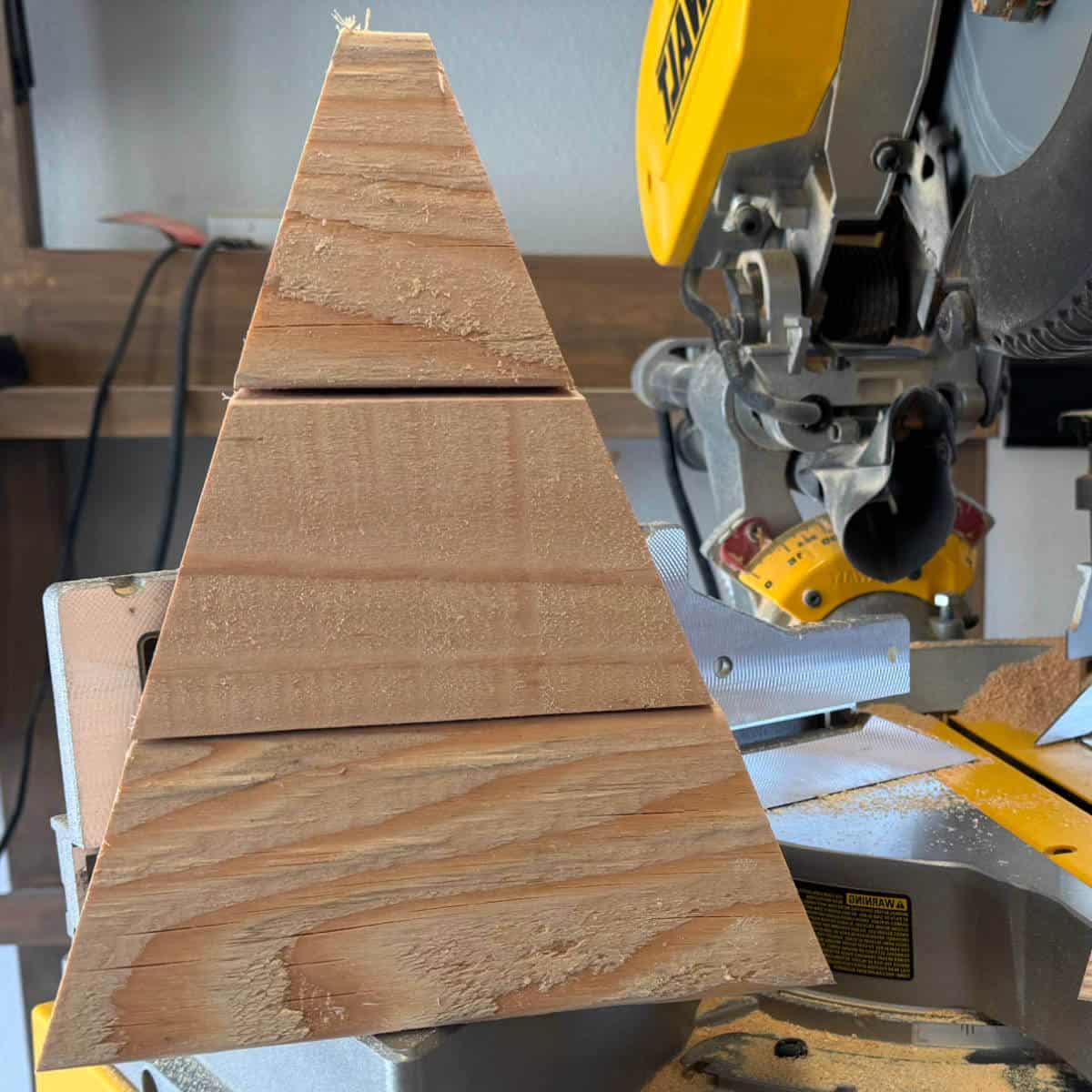 Picture of a 4x4 candy corn as raw wood sitting on a saw.