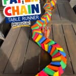 Image of a long table with a colorful paper chain as the table runner.
