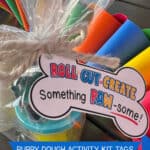 Image of a clear treat bag filled with modeling dough, a dog bone shaped cookie cutter, and a mini rolling pin with a tag attached that says Roll, Cut, Create!