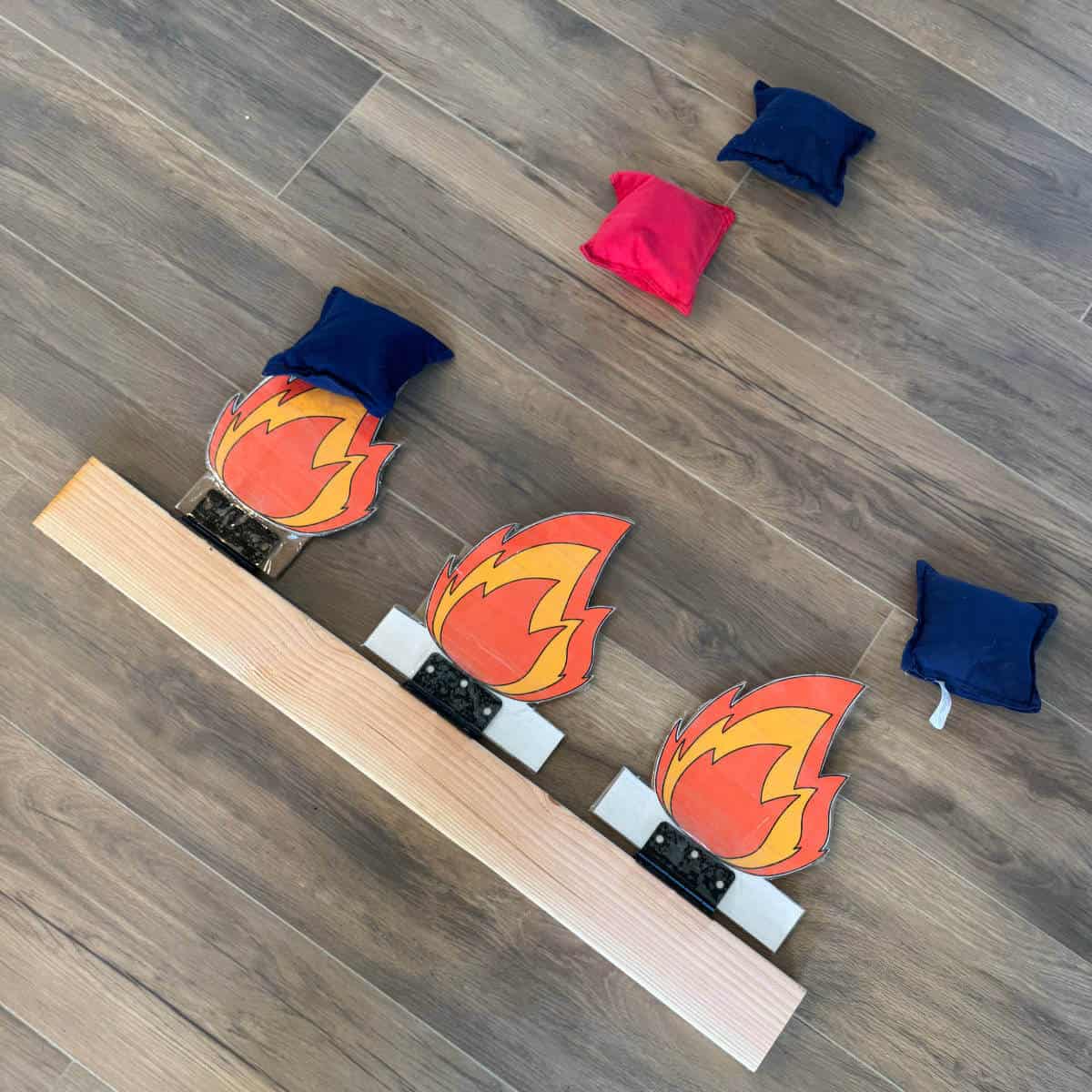 Image of a DIY Put Out The Fire Beanbag Game with the clipart fire knocked over and beanbags all around.